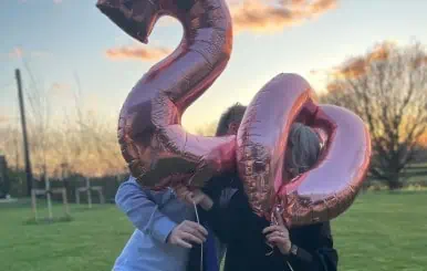 Celebrating 20 years of Lolly Agency with clients holding rose gold balloons shaped as "20" outdoors.