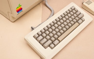 White keyboard and vintage white mac computer with rainbow apple sticker