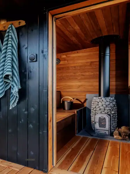 Sauna interior featuring warm wood paneling and a wood-burning stove for relaxation.